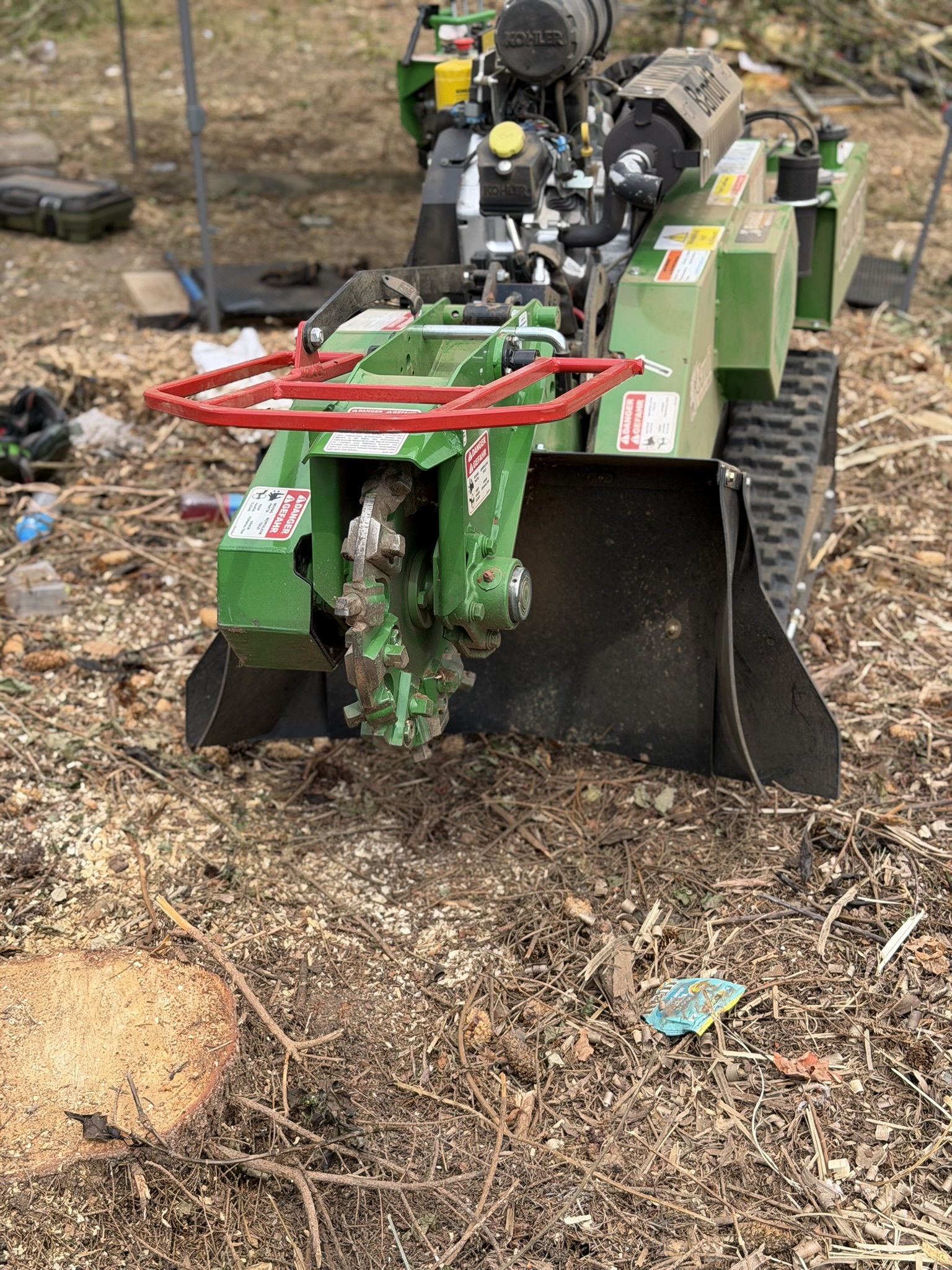 Close-up of the Bandit SG-40 stump grinder cutting wheel over ground covered in grindings and cleared debris on a Romford site clearance